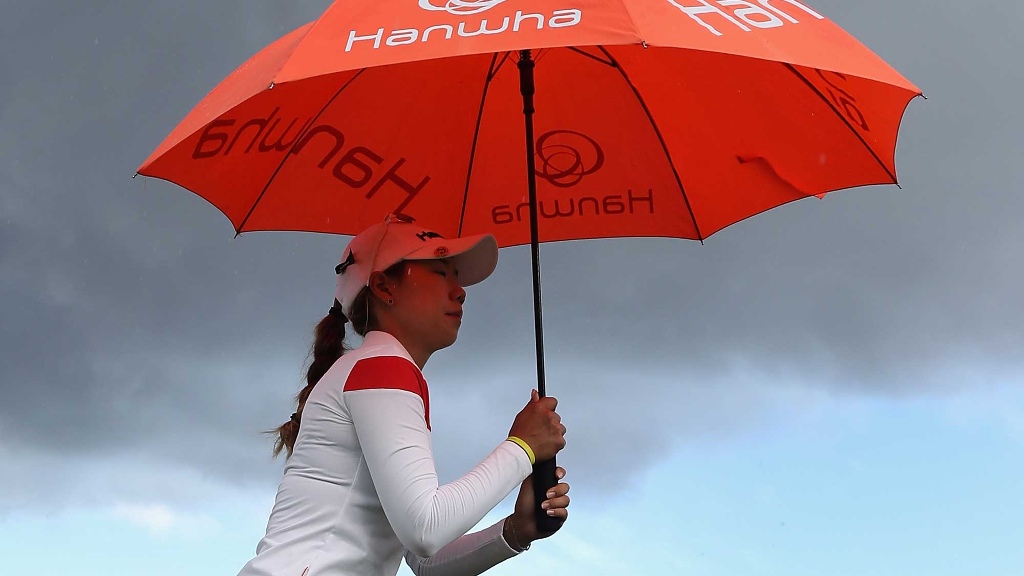 Jenny Shin of the Republic of Korea holds up an umbrella in the rain on the 10th hole during the first round of the LPGA LOTTE Championship Presented By Hershey