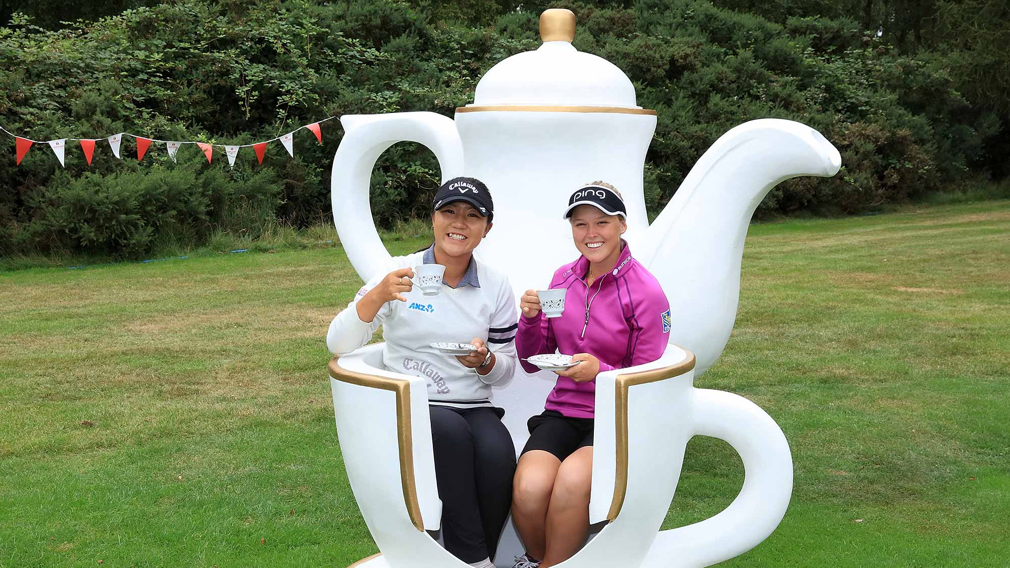 Lydia Ko of New Zealand and Brooke Henderson of Canada (R) attend a traditional English tea party hosted by Charley Hull of England at a photocall during a Pro-Am round ahead of the Ricoh Women's British Open