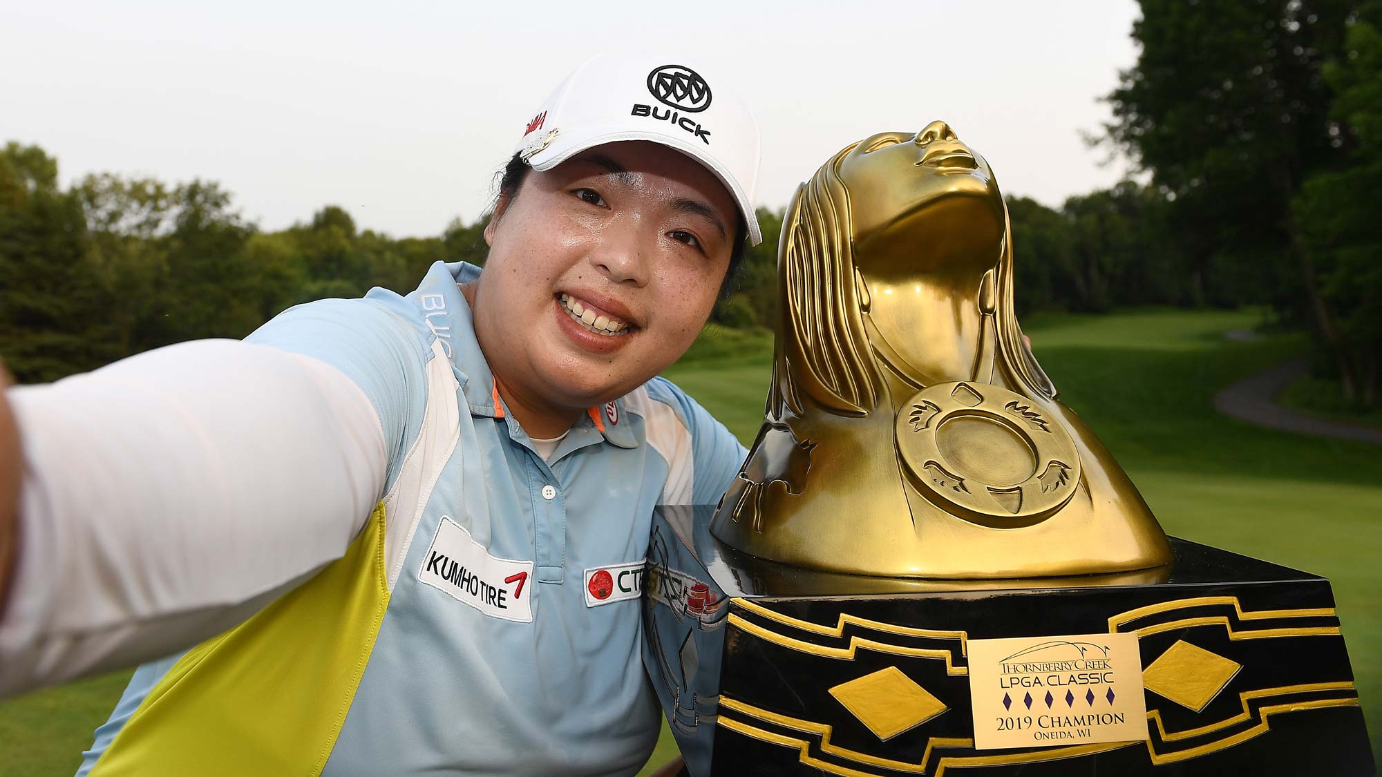 Shanshan Feng of China imitates a "selfie" as she poses with the trophy after winning the Thornberry Creek LPGA Classic
