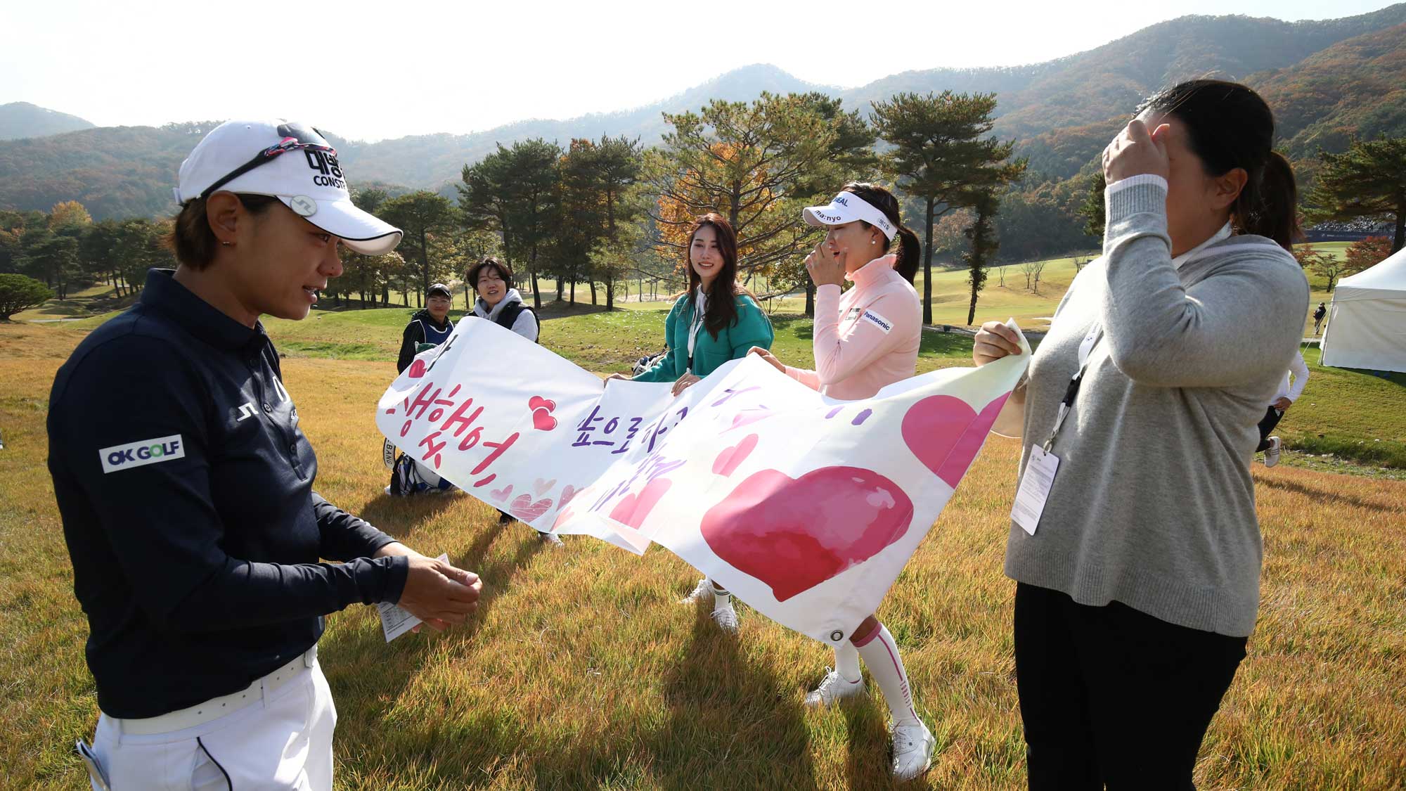 Na-yeon Choi (1st L) of South Korea approaches to Inbee Park (1st R) of South Korea, So-yeon Ryu (2nd R) of South Korea and former player Ha-neul Kim (3rd R) of South Korea holding a banner to appreciate Choi as she is retiring from LPGA tournaments near the 9th green during the final round of the BMW Ladies Championship