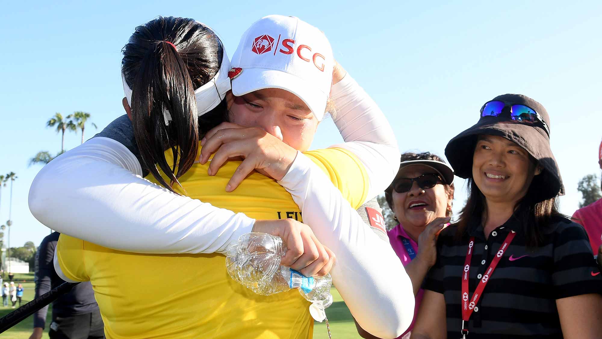 Ariya Jutanugarn of Thailand hugs her sister Moriya Jutanugarn with family on the 18th green in celebration of Moriya's victory in the Hugel-JTBC LA Open at the Wilshire Country Club on April 22, 2018 in Los Angeles, California