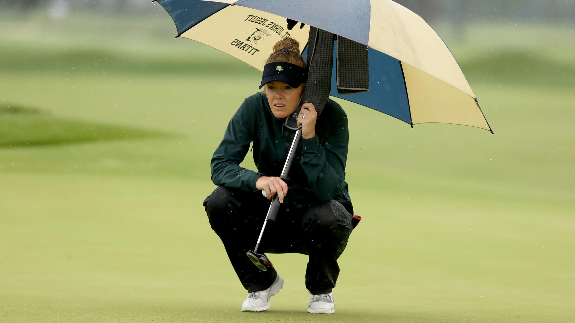 Amy Olson lines up a putt on the second green under an umbrella to avoid the rain during the second round of the LPGA Drive On Championship