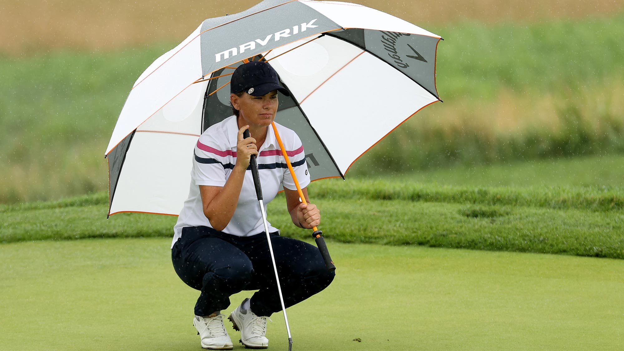 Lee-Anne Pace of South Africa lines up a putt on the fourth green under an umbrella to avoid the rain during the second round of the LPGA Drive On Championship